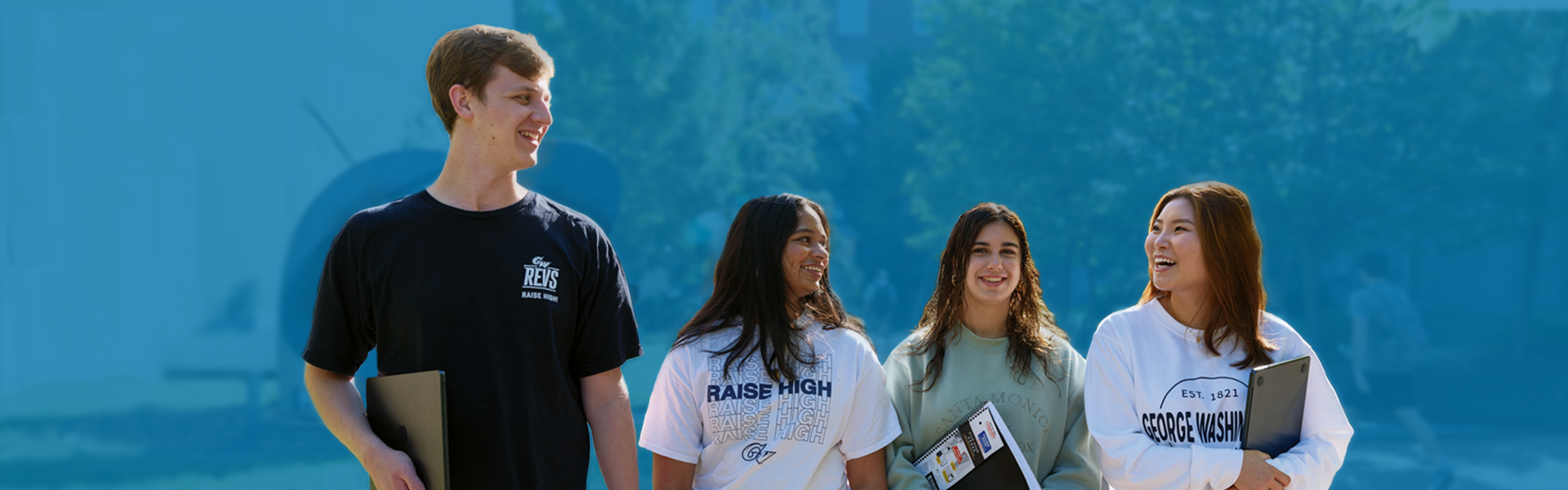 four students walk side by side on GW campus